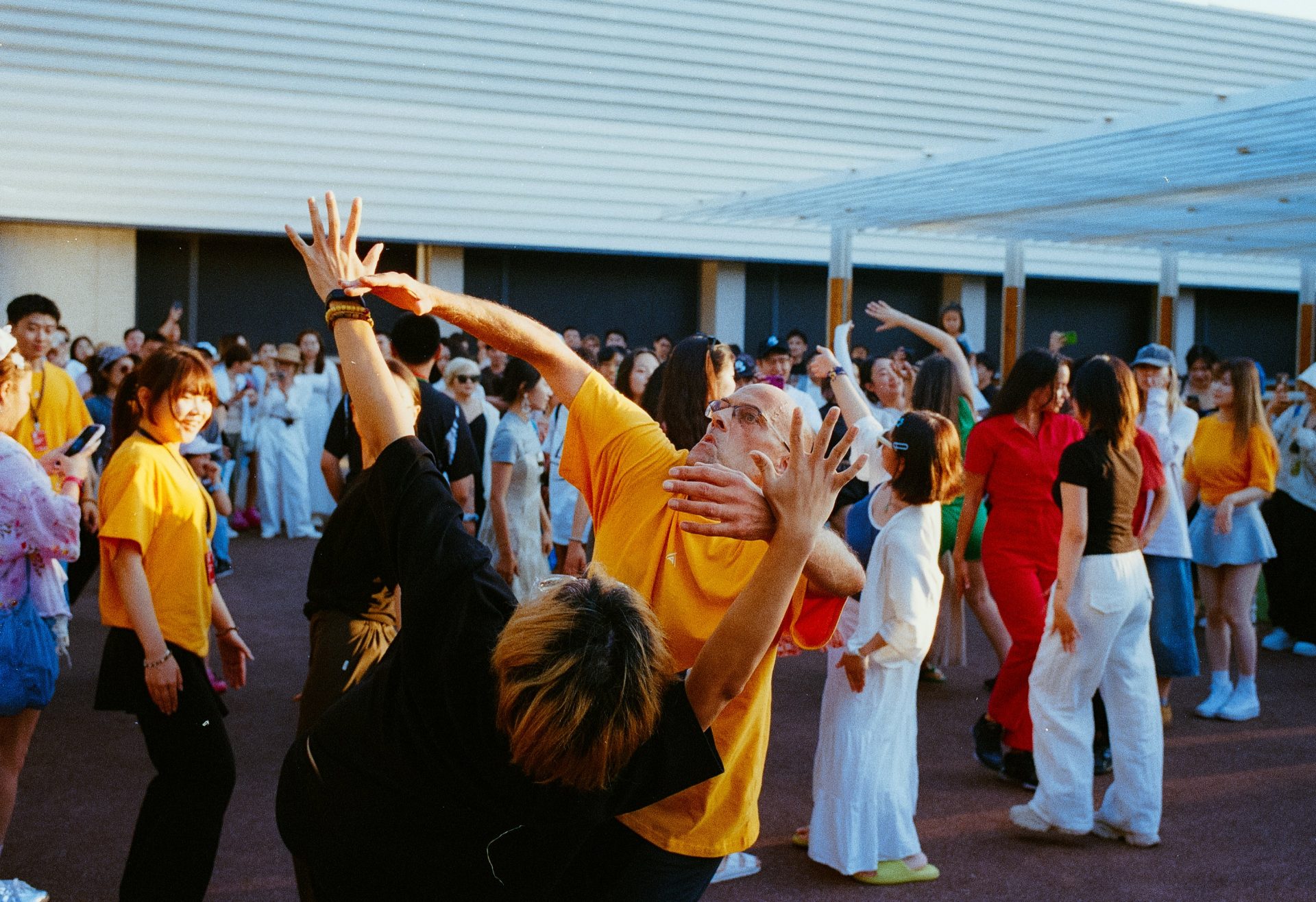 People dance enthusiastically in an outdoor space.